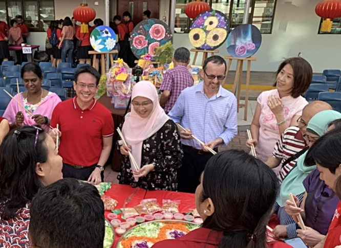 group of teachers standing around a table in Singapore celebrating the Chinese New Year